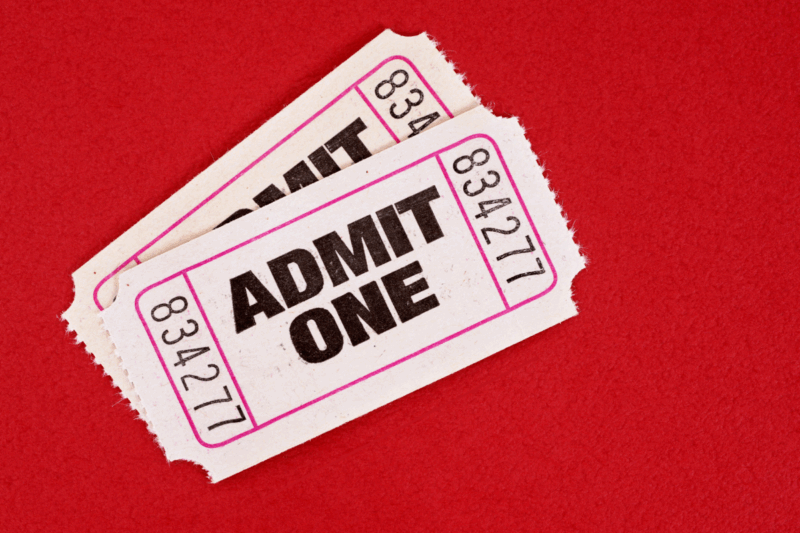 Two old fashioned cinema tickets that say Admit One on them on a red background