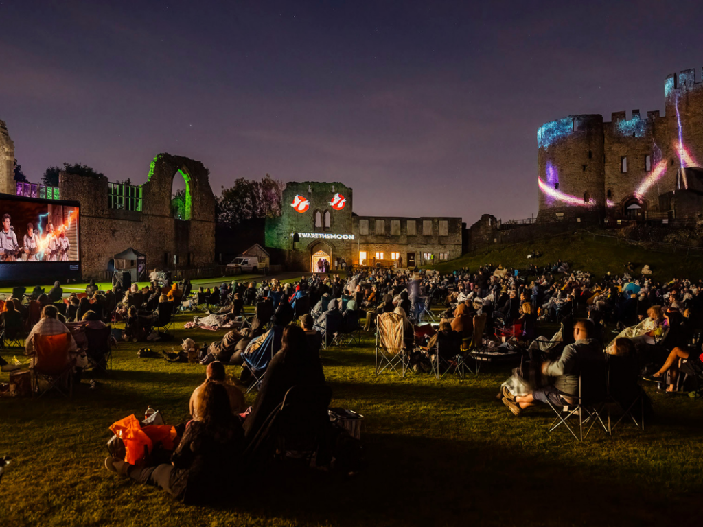 A atmospheric wide angle shot of a night time outdoor screening of Ghostbusters.