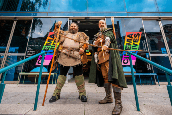 Two men in medieval costumes stand outside Broadway Cinema, Nottingham.