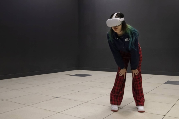 A girl stands in an empty room wearing a VR headset.