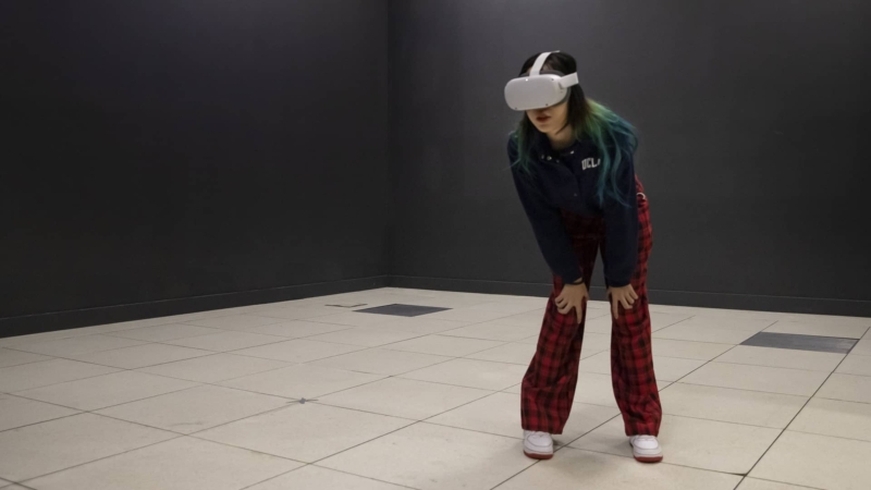 A girl stands in an empty room wearing a VR headset.