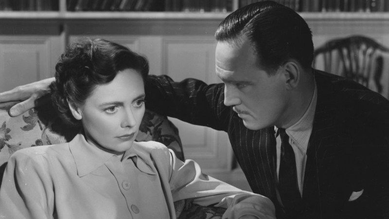 Still from Brief Encounter, a Too Much season title. A black and white image of a woman looking concerned and a man looking at her.