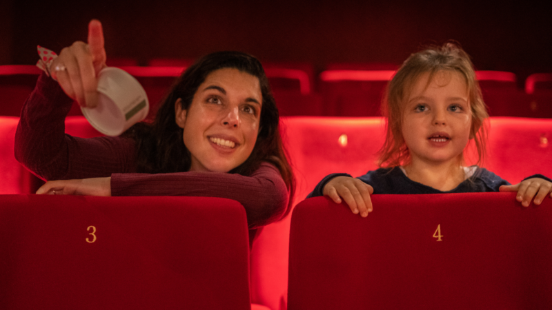 An adult and child sat in a cinema screen